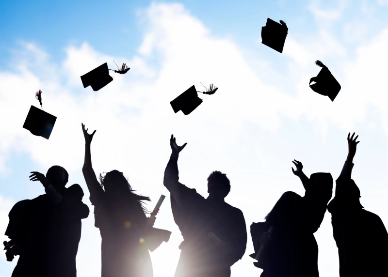 A group of people that are throwing their hats in the air.