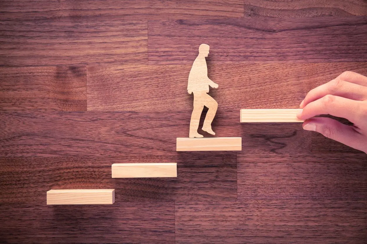 A wooden figure of a person climbing up some steps